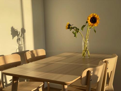 a dining room table with a vase of sunflowers on it at Queensview168 Apartments Moonee Ponds in Melbourne