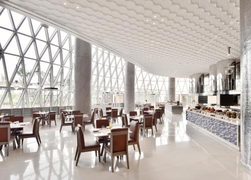 a restaurant with tables and chairs and large windows at JW Marriott Hotel Kolkata in Kolkata