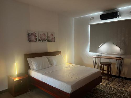 1 dormitorio con 1 cama y escritorio con lámpara en Smart Stay Eco Friendly AirBnB, en Lusaka