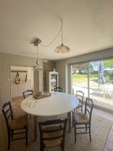 une salle à manger avec une table et des chaises blanches dans l'établissement fermette, à Plounévez-Lochrist