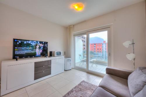 ein Wohnzimmer mit einem TV und einem großen Fenster in der Unterkunft Prestige du Lac 27 - Happy Rentals in Lugano