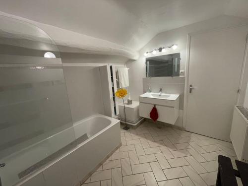 a white bathroom with a tub and a sink at Maison de ville cosy et chaleureuse 