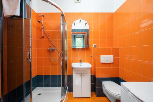 an orange bathroom with a toilet and a sink at Obrzeżna Standard Apartment in Warsaw