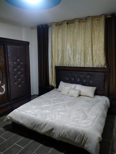 a bedroom with a large bed with a wooden headboard at شقة فاخرة مع مطل in Amman