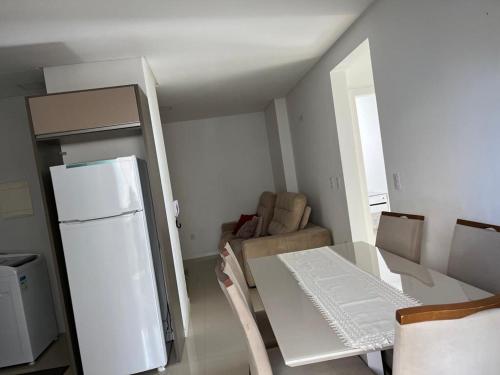 a kitchen with a white refrigerator and a table and chairs at Apartamento à 400m do mar in Itapema