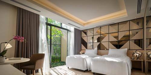 a bedroom with two beds and a table and a window at PARKROYAL Langkawi Resort in Pantai Cenang