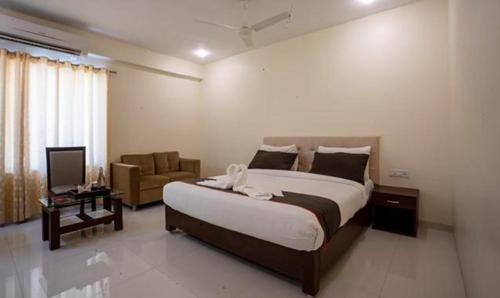 una camera con un grande letto e una sedia di FabHotel Prime Lorven a Visakhapatnam