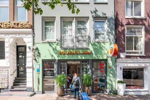 a woman walking down a street in front of a store at Budget Hotel Tourist Inn in Amsterdam