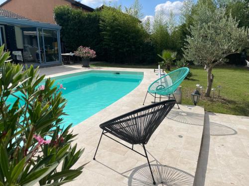 deux chaises assises à côté d'une piscine dans l'établissement Villa poétique proche de Lyon, à Saint-Marcel-en-Dombes
