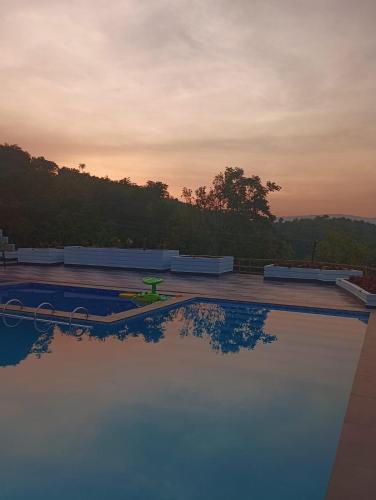 a swimming pool with a sunset in the background at The Arcadia Pool and Villa - Umroi in Shillong