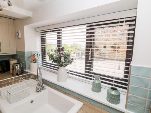 a kitchen with a sink and a window with blinds at Smithy Cottage in Dronfield