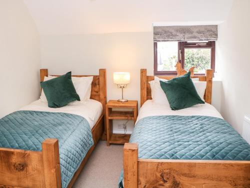 two twin beds in a room with a window at Smithy Cottage in Dronfield