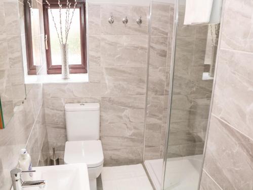 a bathroom with a shower and a toilet and a sink at Smithy Cottage in Dronfield
