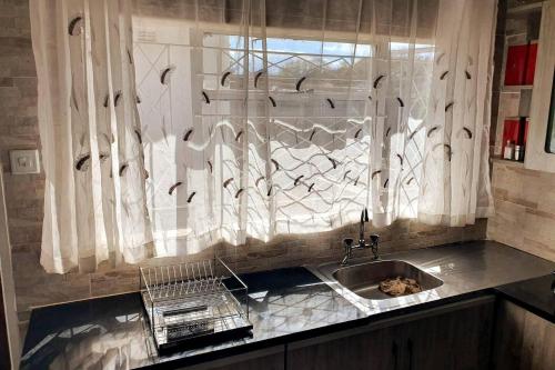 a kitchen with a sink and a window at Secure solar powered two bedroomed haven in Harare