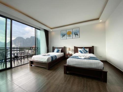 a bedroom with two beds and a balcony at VANG VIENG TOPVIEW HOTEL in Vang Vieng