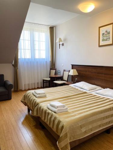 a hotel room with a large bed with towels on it at Hotel Kresowiak in Siemiatycze