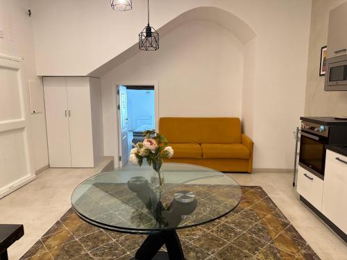 ein Wohnzimmer mit einem Glastisch mit einer Blumenvase in der Unterkunft Dal Console - Piazza Bellini - Napoli in Neapel