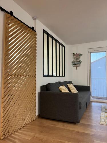 a living room with a couch and a wooden sliding door at Perle rare à 250m de la plage ! Climatisé avec Parking, balcon & WiFi in Sainte-Maxime