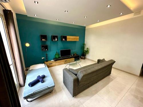 a living room with a couch and a tv at Sunset Apt Modern 1 bedroom Apt near the Beach in Birżebbuġa