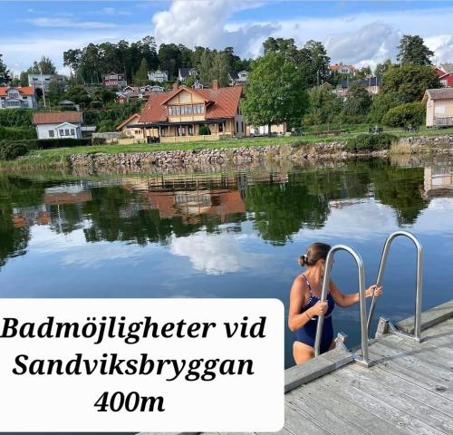 a woman sitting on a dock next to a body of water at Villa Kolmården in Kolmården