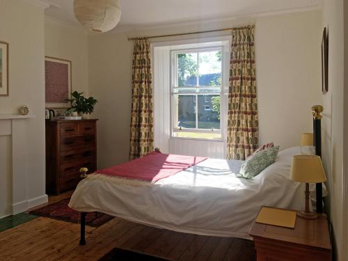 Schlafzimmer mit einem Bett und einem Fenster in der Unterkunft Rutherford House in Town Yetholm