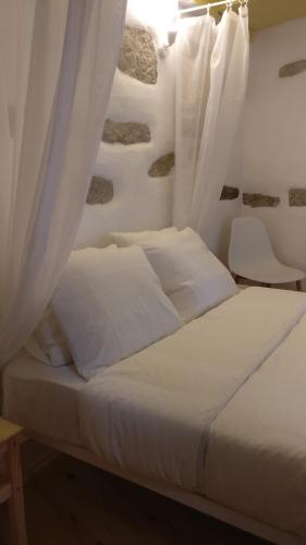 a bed with white sheets and curtains in a room at Casinhas de S. Francisco T1 Amêndoa by LovelyStay in Freixo de Espada à Cinta