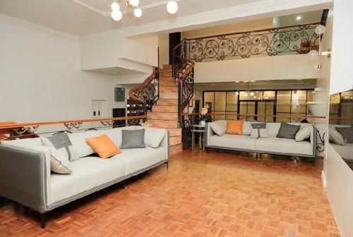 a living room with two couches and a staircase at Honey Suite Room 2 inside Bee Cafe Cebu at Ayala Area in Cebu City