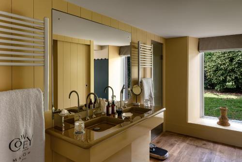 a bathroom with two sinks and a large mirror at Cowley Manor Experimental in Cheltenham
