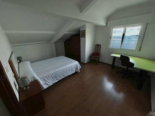 a bedroom with a bed and a desk and a window at Casa Independiente Bella Vista in Moaña