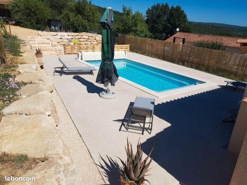 - une piscine avec un parasol, une chaise et une table dans l'établissement Gîte Lavalette09 Ardèche et Cèze, à Saint-Christol-de-Rodières