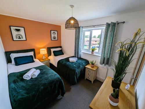 Habitación de hotel con 2 camas y ventana en 6 Guests * 4 Bedroom * Free Wi-Fi en Burton Latimer
