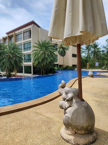 una estatua de un animal de piedra sosteniendo un paraguas frente a una piscina en Apartment en Ban Mae Nam