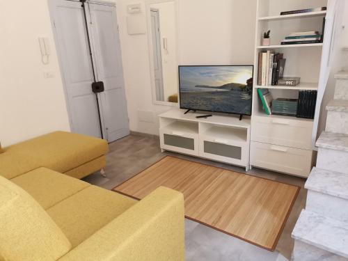 a living room with a yellow couch and a television at Da amènte in Alassio