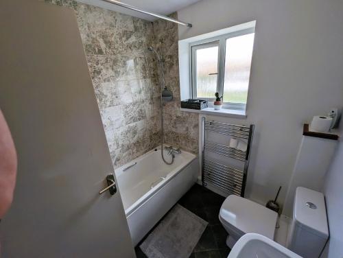 a bathroom with a tub and a toilet and a sink at 6 Guests * 4 Bedroom * Free Wi-Fi in Burton Latimer