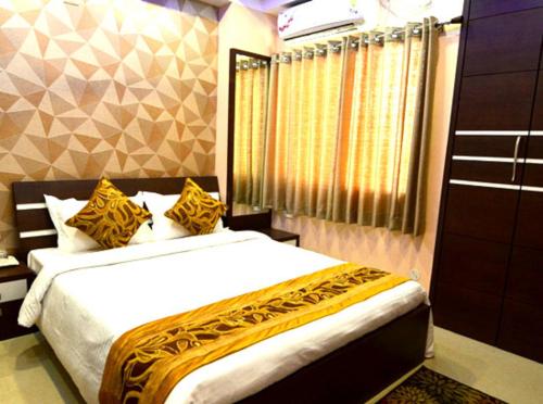 a bedroom with a bed with yellow and white sheets at Tulip Residency in Dibrugarh