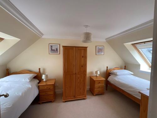 a bedroom with two beds and a window at Primrose Cottage in Killean