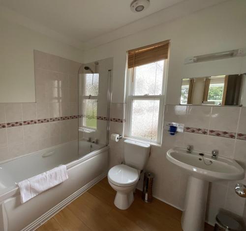 a bathroom with a toilet and a tub and a sink at Primrose Cottage in Killean