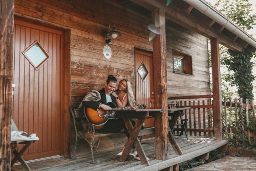 a man and woman sitting at a table on the porch of a cabin at Kultur Weingut Kästenburg in Ratsch an der Weinstraße