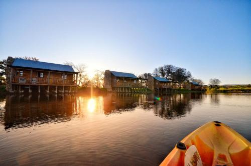 a boat in the water near some houses on a river at De Zeekoe Guest Farm in Oudtshoorn