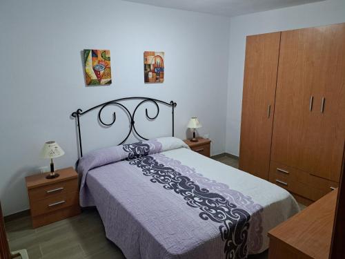 1 dormitorio con 1 cama con colcha púrpura y armarios de madera en BLANCO, en Las Playitas