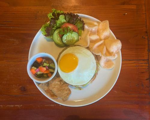 a plate of food with an egg and vegetables and chips at Griya Shanti Suites in Sanur