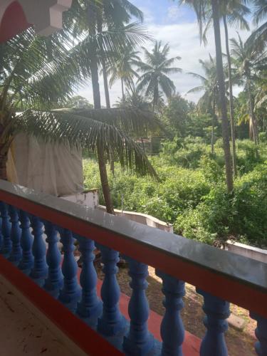 a balcony with palm trees in the background at INAS Guest House in Canacona