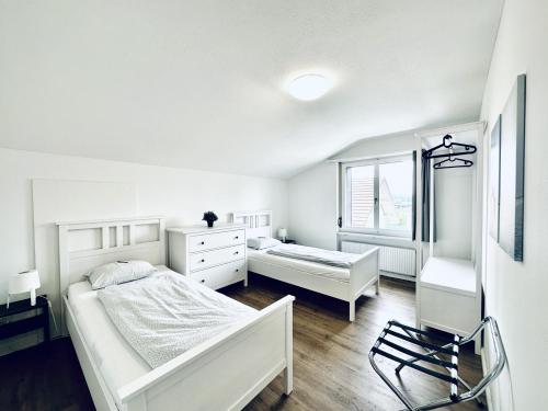 a white bedroom with two beds and a window at Monteurzimmer ZIMMERzuVERMIETEN in Deitingen Neumatt in Deitingen