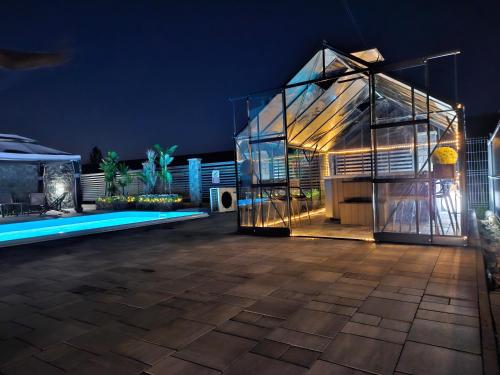 a glass house with a swimming pool at night at Apartamenty pod Gromadzyniem in Ustrzyki Dolne