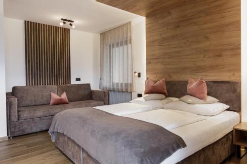 a bedroom with a large bed and a couch at Aparthotel Familiaris - Family Apartments - Pools & Spa in Dolomites in Valdaora