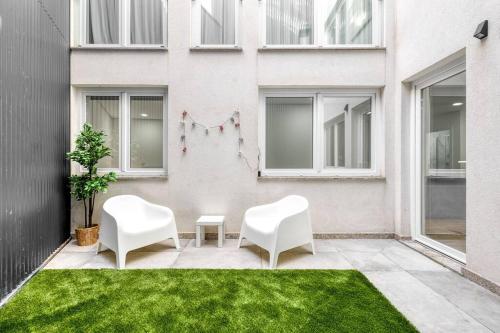 two white chairs on a patio in front of a building at Cosy flat, Braga city center in Braga