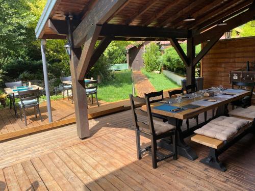 a patio with a table and chairs on a wooden deck at Un nid de verdure 2 ch in Sirod