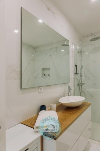 a white bathroom with a sink and a mirror at Smilling waves in Fão