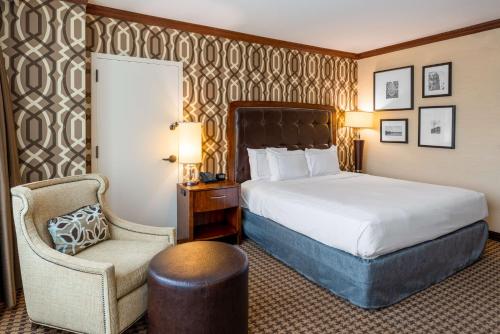 a hotel room with a bed and a chair at Hilton Alexandria Mark Center in Alexandria