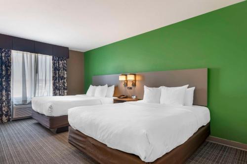 two beds in a hotel room with green walls at Comfort Suites Conference Center Rapid City in Rapid City